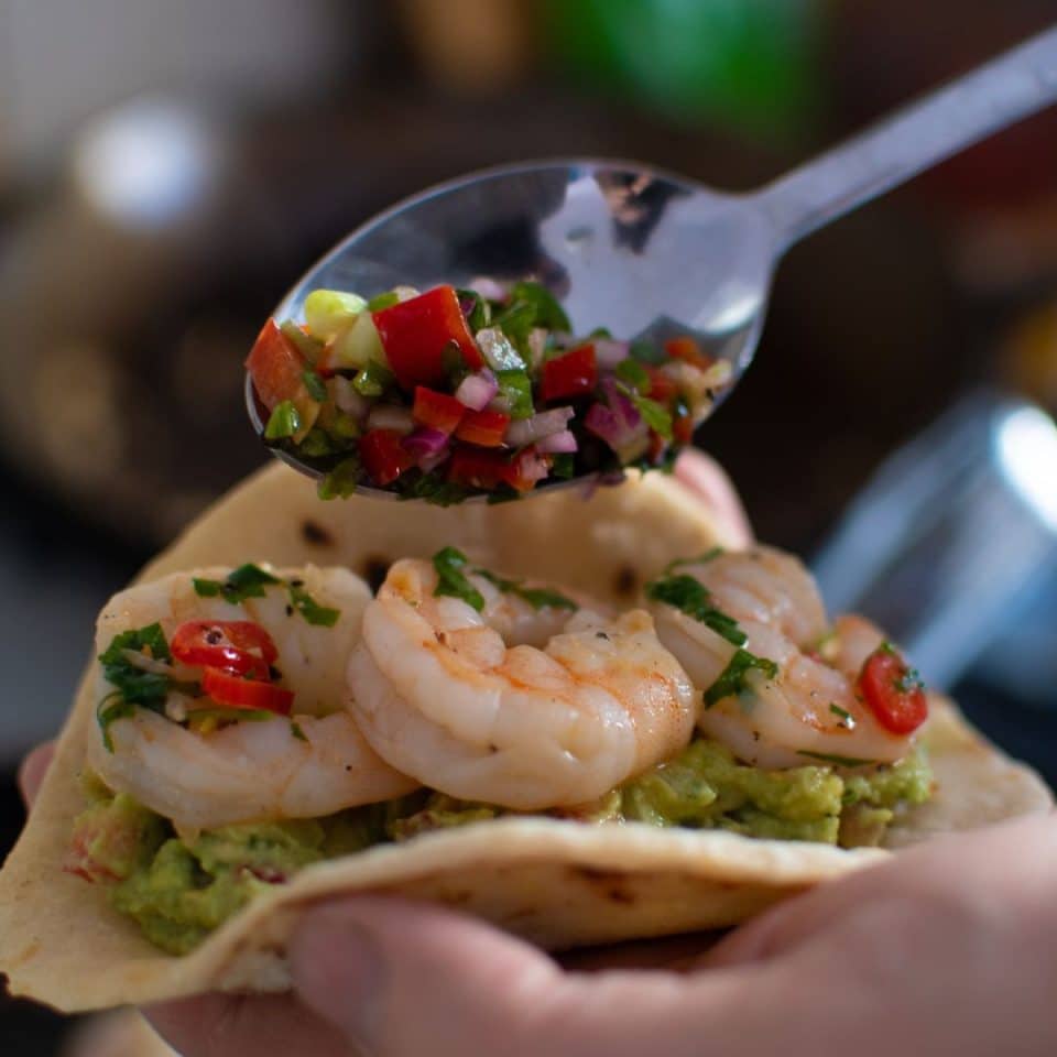 Adding salsa to shrimp tacos