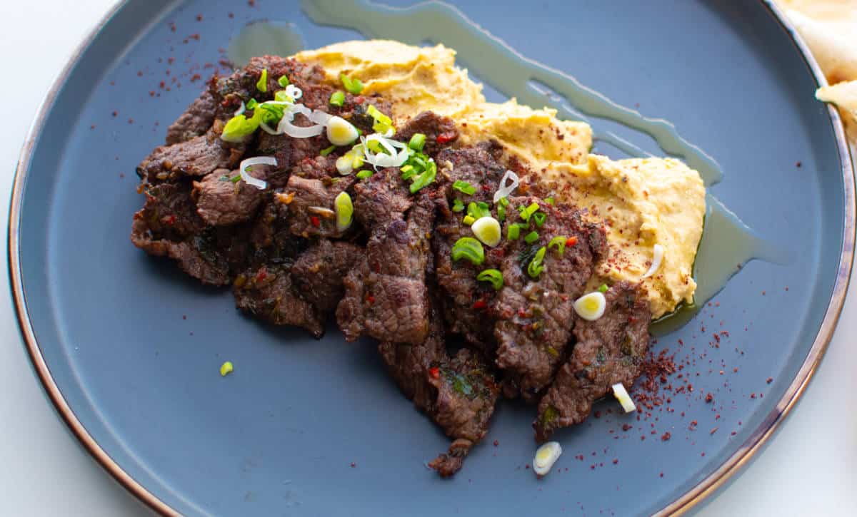 Thinly sliced ribeye with hummus and capers